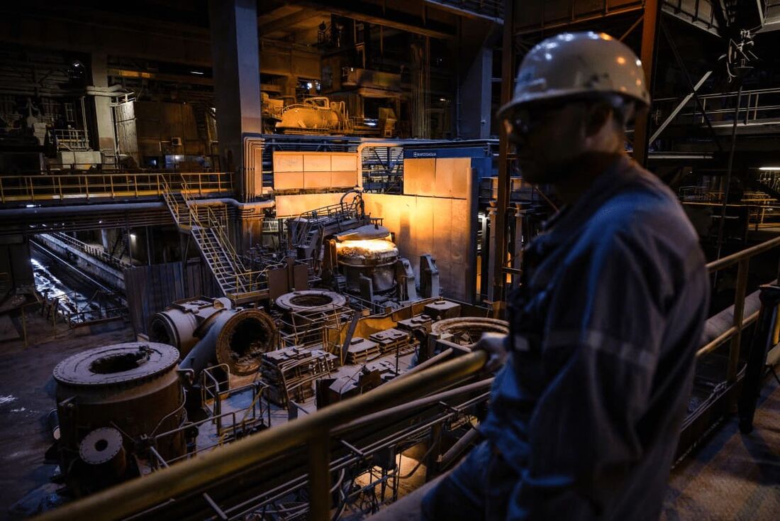 Um trabalhador em pé na fábrica enquanto um forno a arco elétrico opera na siderúrgica Marcegaglia em Fos-sur-Mer, sul da França, em 24 de março de 2025.