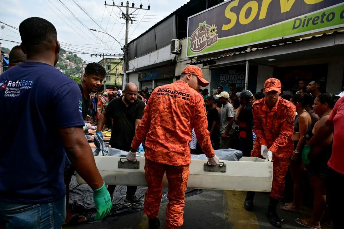 Bombeiros e moradores carregam um corpo na Praça São Lucas, na favela Vila Cruzeiro, no complexo da Penha, Rio de Janeiro