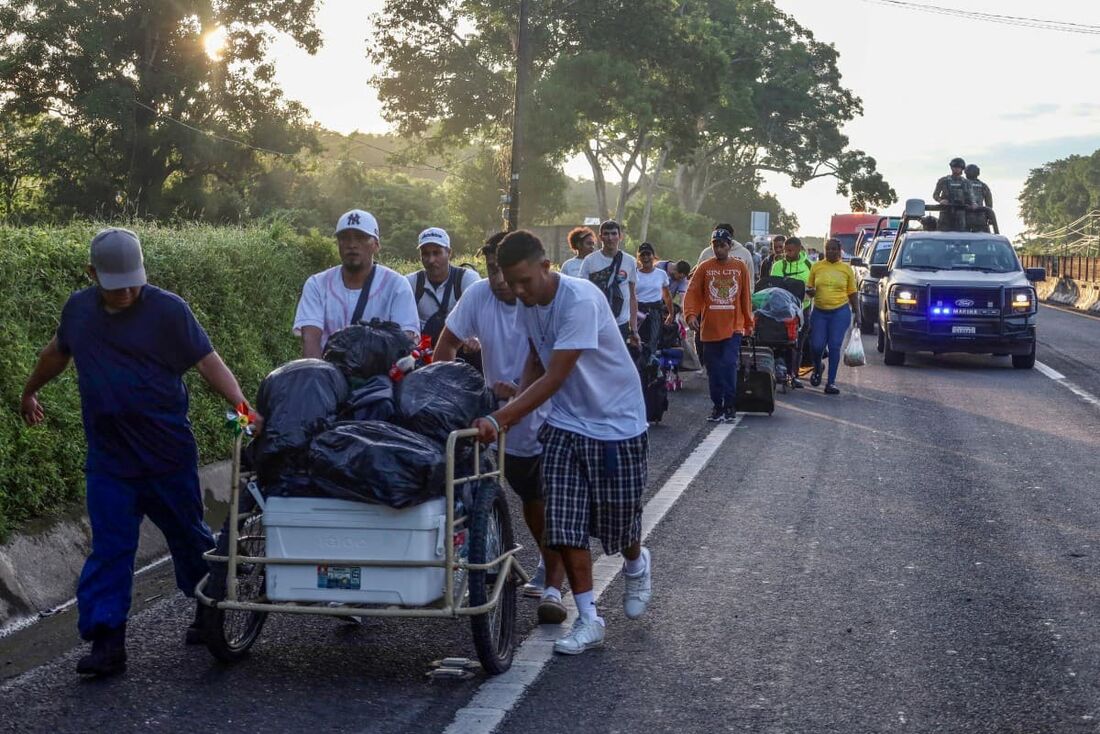 Imigrantes são escoltados por patrulhas do exército mexicano enquanto caminham pela rodovia como parte de uma caravana que busca chegar à capital mexicana