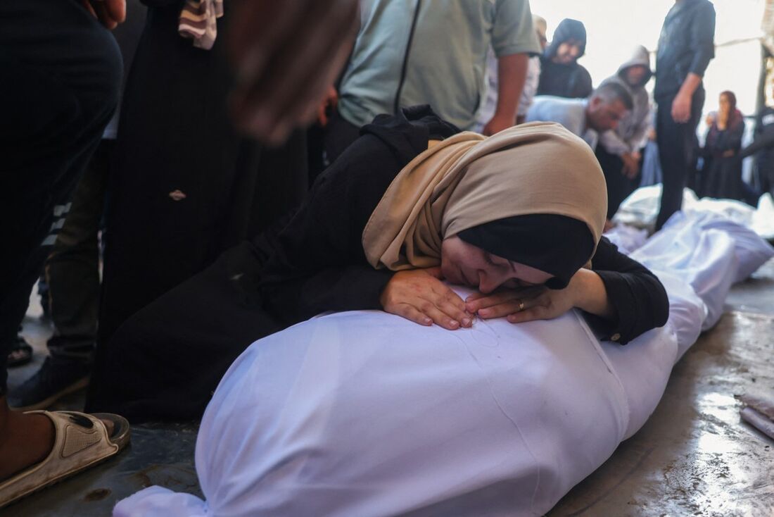 Palestinos lamentam o corpo de um parente morto em ataques israelenses em Deir al-Balah, no Hospital dos Mártires de Al-Aqsa, no centro da Faixa de Gaza,