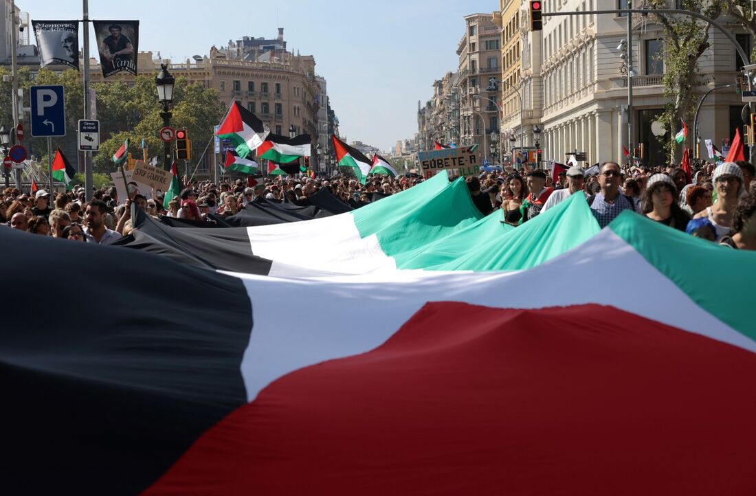 Participantes seguram uma bandeira palestina gigante durante uma manifestação em solidariedade aos palestinos em Barcelona