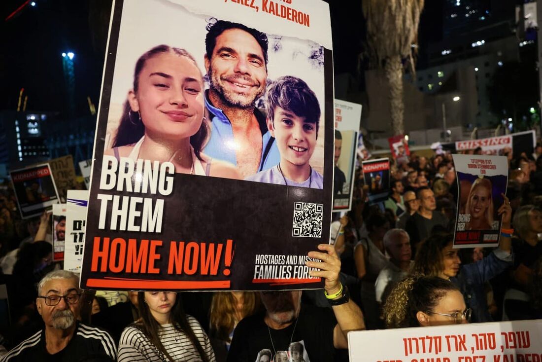 Manifestantes erguem cartazes em protesto em Tel Aviv, em 18 de novembro de 2023, para exigir a libertação dos israelenses mantidos reféns em Gaza