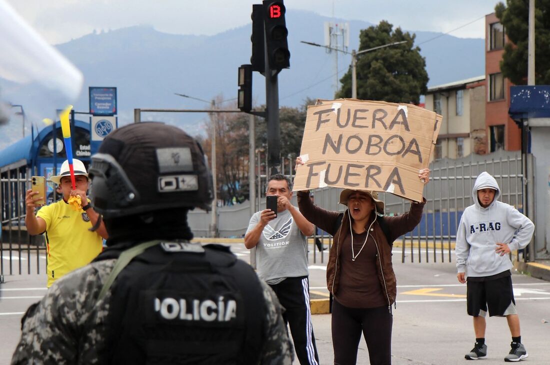 Uma manifestante segura uma placa com os dizeres "Noboa Fora"
