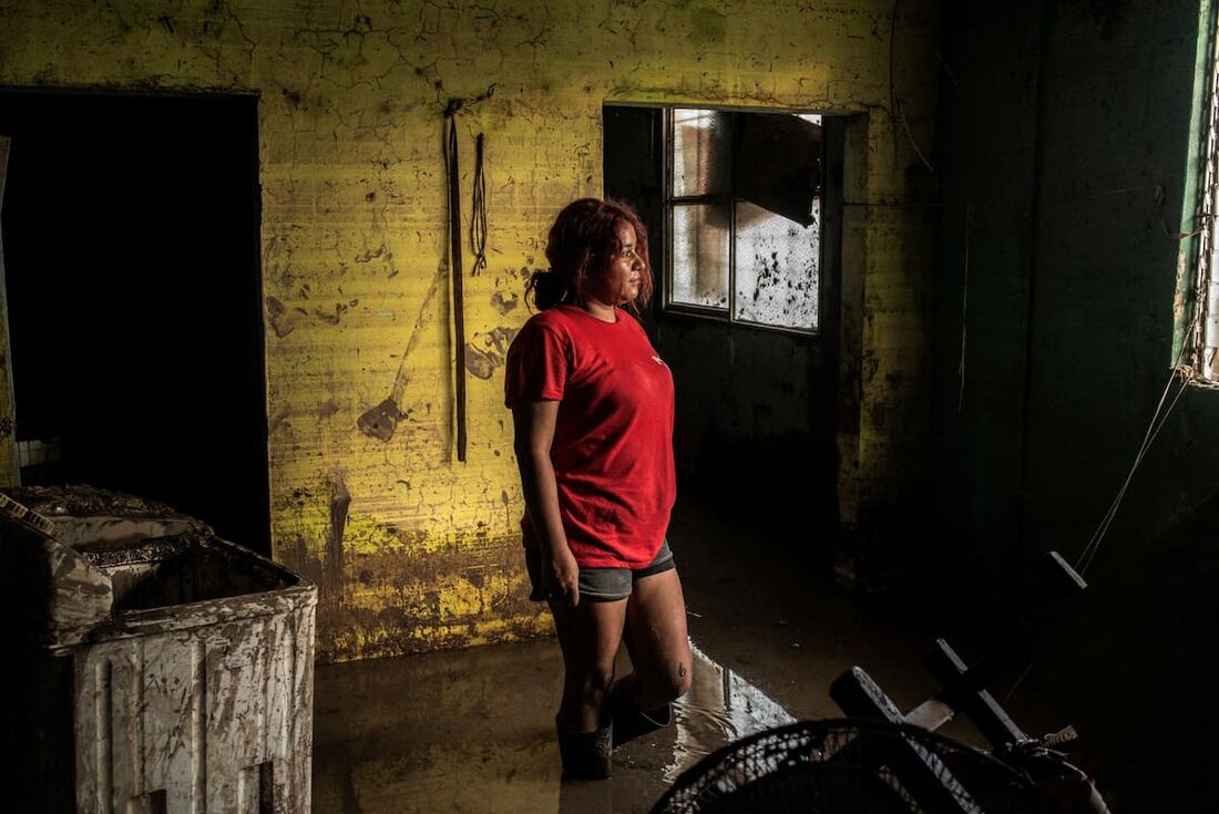 Uma mulher olha para dentro de uma casa coberta de lama e detritos causados pelas fortes chuvas no bairro de Las Granjas em Poza Rica, estado de Veracruz, México