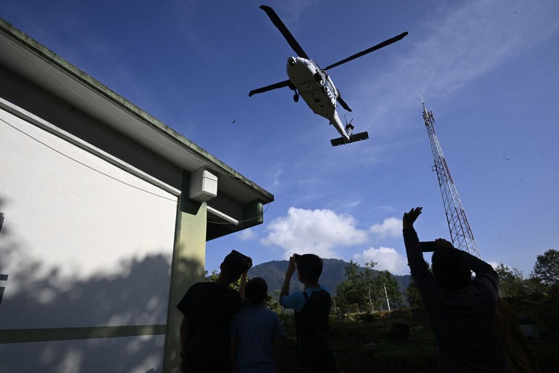 Crianças assistem ao pouso de um helicóptero para entregar ajuda fornecida pela Guarda Nacional do México e pela Secretaria de Defesa Nacional
