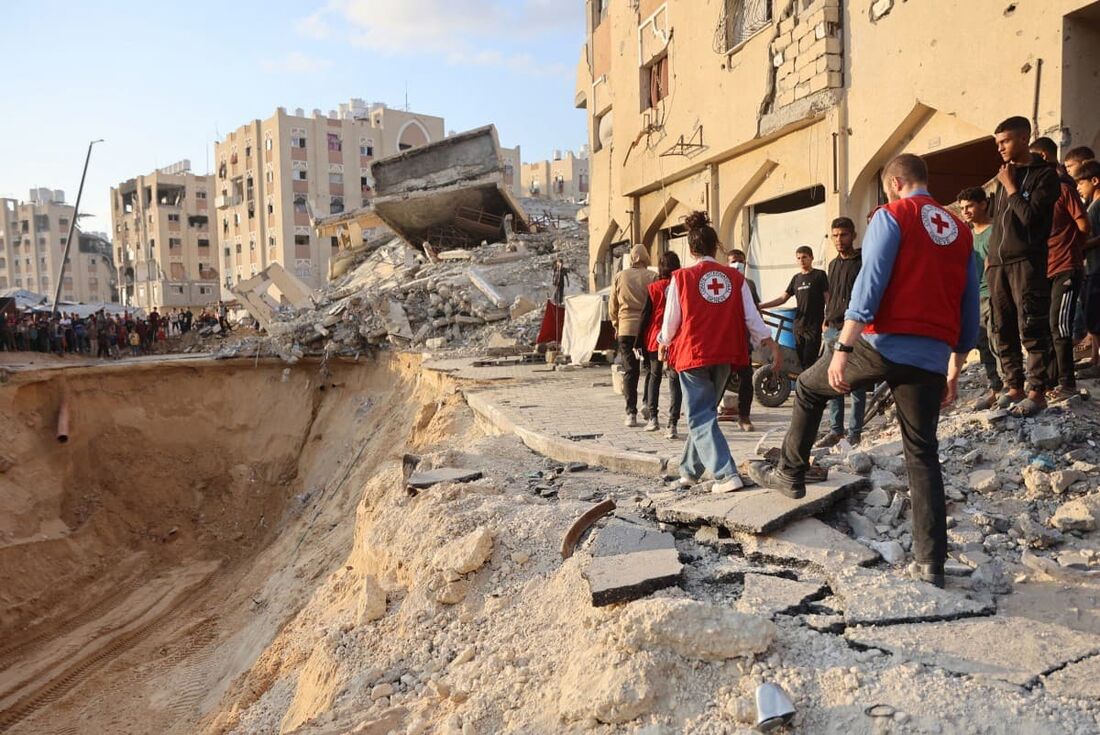 Membros da Cruz Vermelha e população se reúnem em um local em busca de corpos em Khan Yunis, no sul da Faixa de Gaza