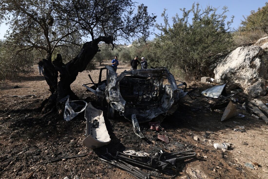 Palestinos observam os destroços de um veículo no local onde três palestinos foram mortos por forças israelenses durante um ataque na vila de Kafr Qud, perto da cidade de Jenin, na Cisjordânia ocupada por Israel, em 28 de outubro de 2025