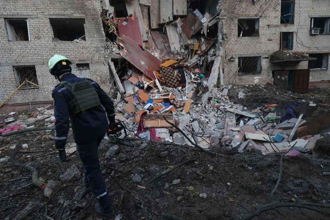 Um socorrista ucraniano caminha entre os escombros no local de um prédio gravemente danificado após um ataque aéreo em Zaporizhzhia