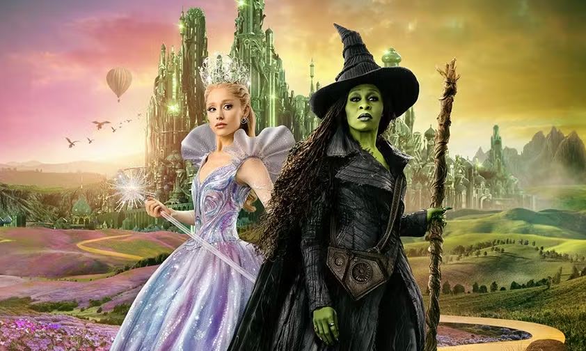 Ariana Grande e Cynthia Erivo em cartaz de "Wicked: Parte II" -  A visita está sendo promovida pela Universal Pictures e pela TV Globo, quem compartilhou a novidade em post nas redes sociais.