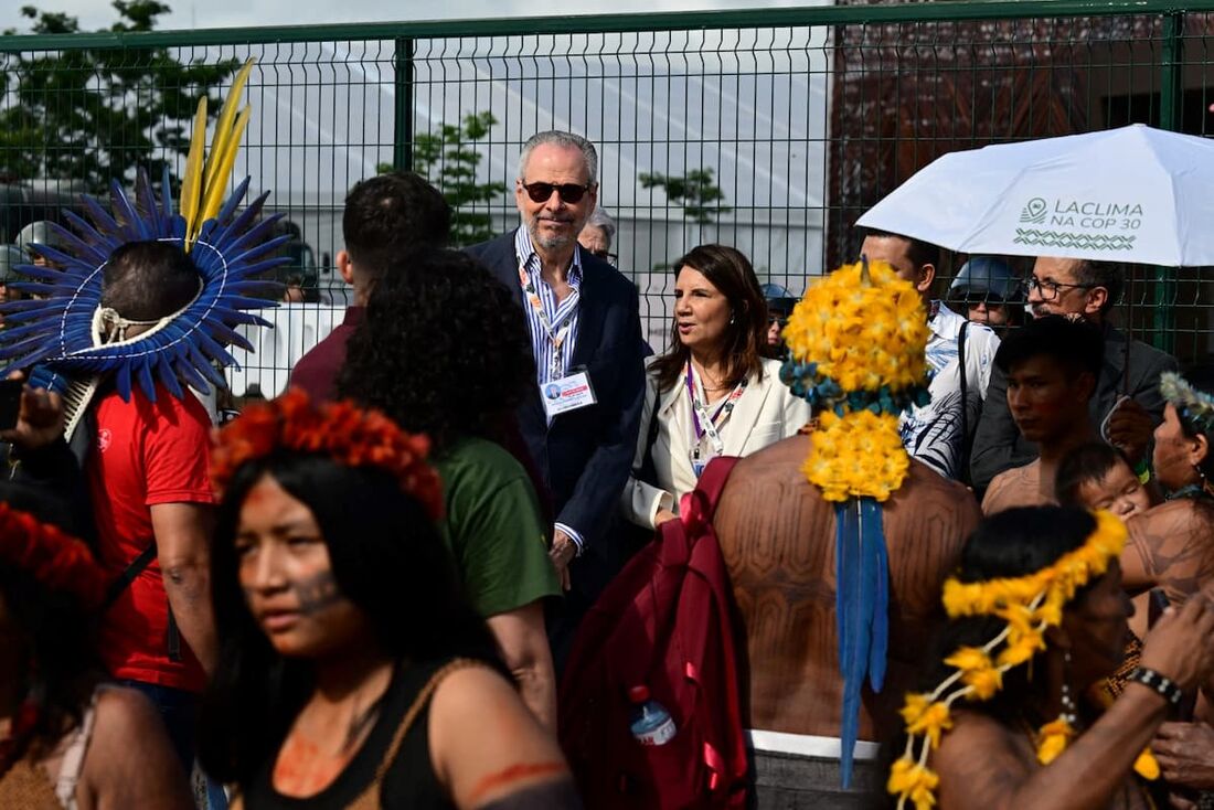 O presidente da COP30, André Correa do Lago, conversa com a diretora-executiva brasileira da COP30, Ana Toni, cercados por indígenas Munduruku