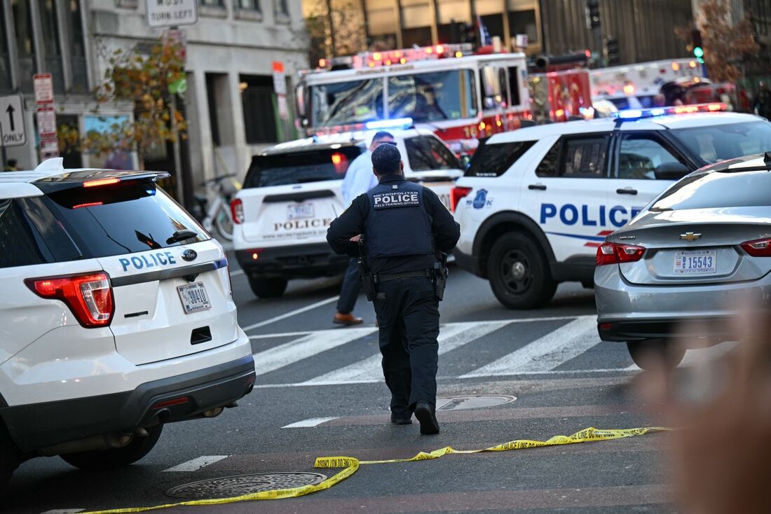Um policial da Polícia Metropolitana caminha entre viaturas perto da cena de um crime após um tiroteio no centro de Washington, D.C., em 26 de novembro de 2025.