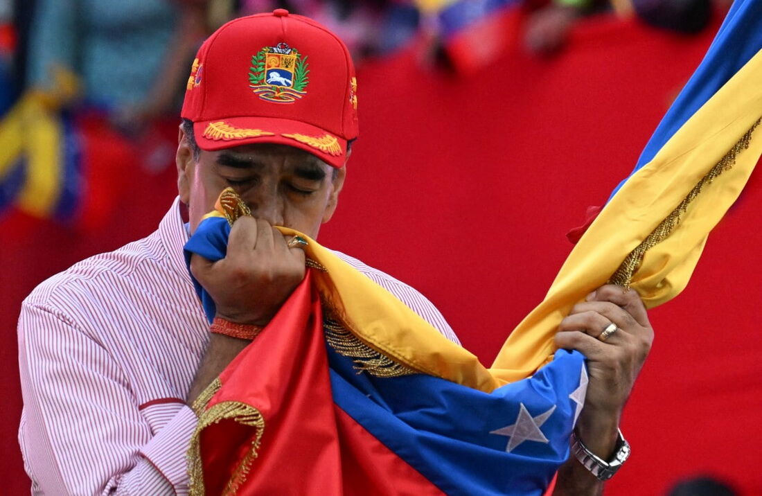 O presidente da Venezuela, Nicolás Maduro, beija a bandeira nacional durante um comício em Caracas