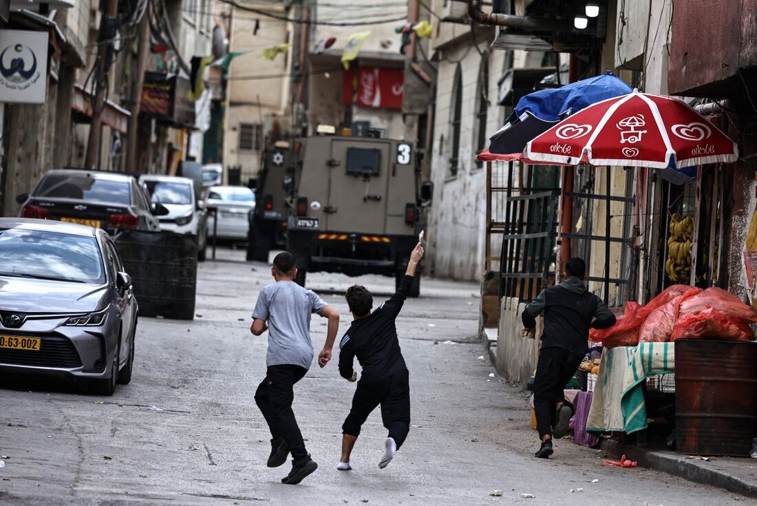 Crianças jogam pedras em um veículo israelense em Ramallah, Territórios Palestinos