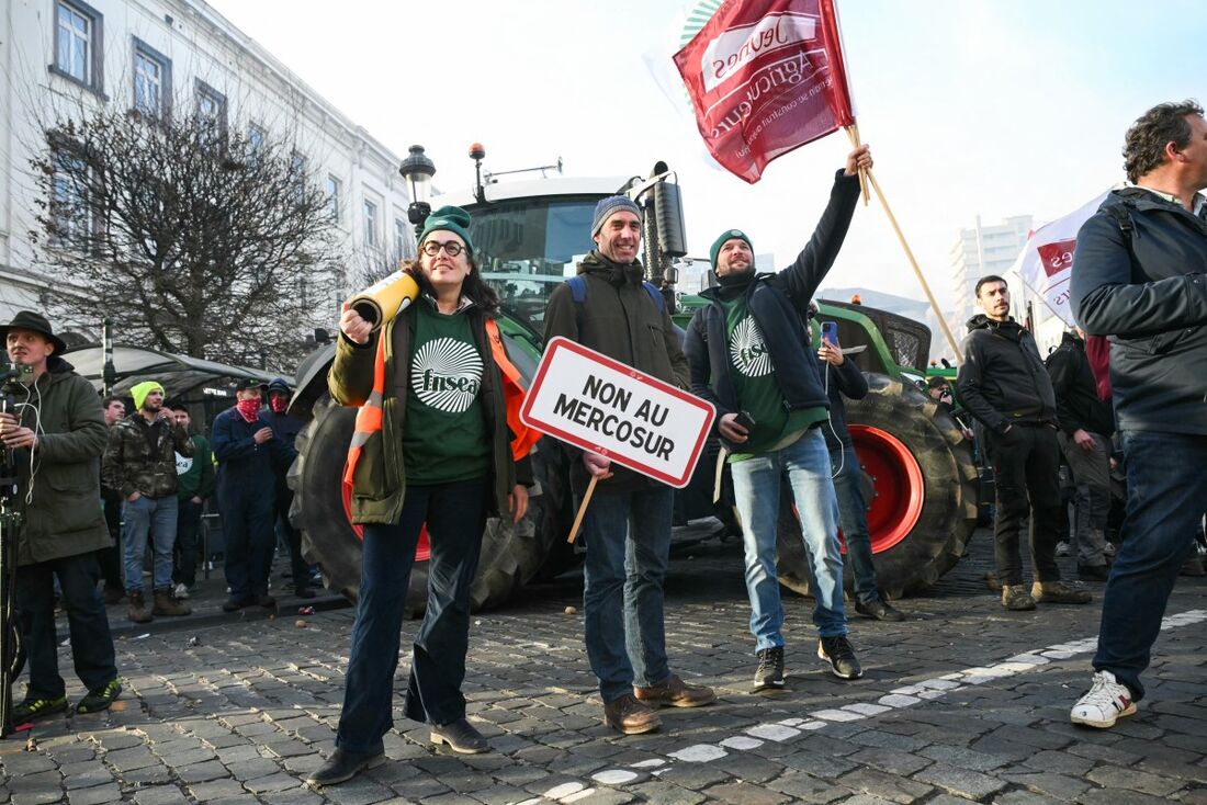 Manifestantes exibem cartazes com os dizeres "Não ao Mercosul" e bandeiras da principal associação de agricultores da França, a FNSEA (Federação Nacional dos Sindicatos de Exploradores Agrícolas) e da Jeunes Agriculteurs (JA, Jovens Agricultores)