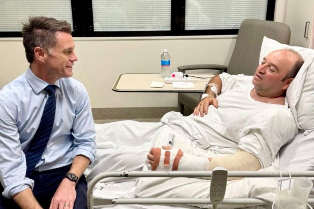 O Primeiro-Ministro de Nova Gales do Sul, Chris Minns (à esquerda), conversando com Ahmed Al Ahmed, o homem que imobilizou e desarmou um dos agressores da praia de Bondi, no Hospital St. George, em Sydney.