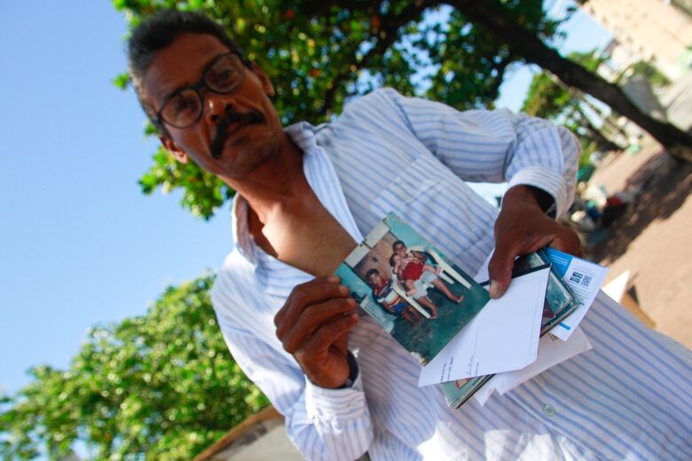 Nas mãos do pedreiro, fotos da família retratam o homem que nem sempre esteve nesta situação (Foto: Melissa Fernandes/Folha de Pernambuco)