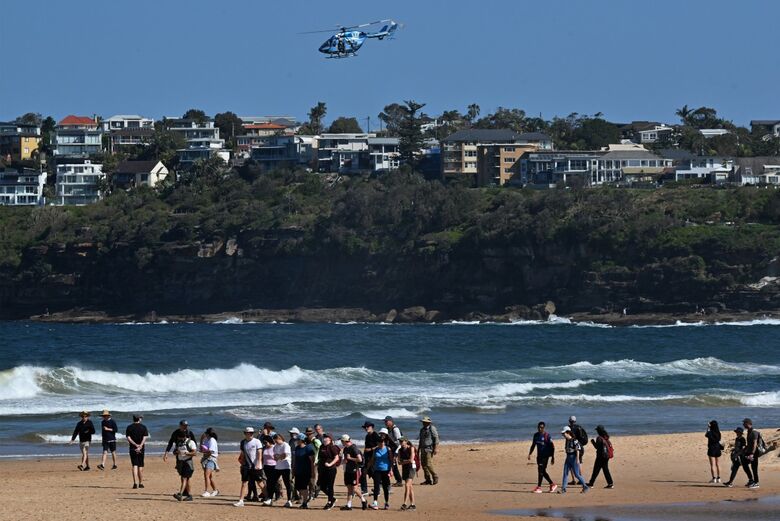 Banhistas e surfistas tiveram que deixar o mar de Sidney, na Austrália, após autoridades fecharem a praia por conta do ataque de tubarão que matou um homem. - Foto: Saeed Khan/AFP