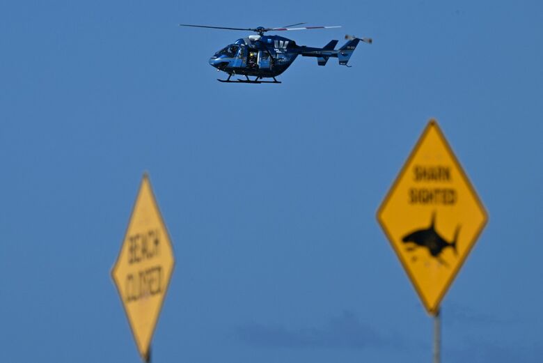 Banhistas e surfistas tiveram que deixar o mar de Sidney, na Austrália, após autoridades fecharem a praia por conta do ataque de tubarão que matou um homem. - Foto: Saeed Khan/AFP