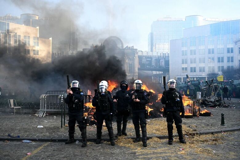 Agentes da polícia evacuam a Praça de Luxemburgo, perto do Parlamento Europeu, durante um protesto de agricultores contra as reformas da Política Agrícola Comum (PAC) e acordos comerciais como o Mercosul, em Bruxelas. | Foto: AFP