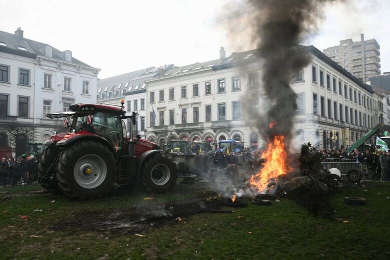 Agricultores protestam ao lado de tratores e de uma fogueira perto do Parlamento Europeu, na Praça de Luxemburgo. | Foto: AFP