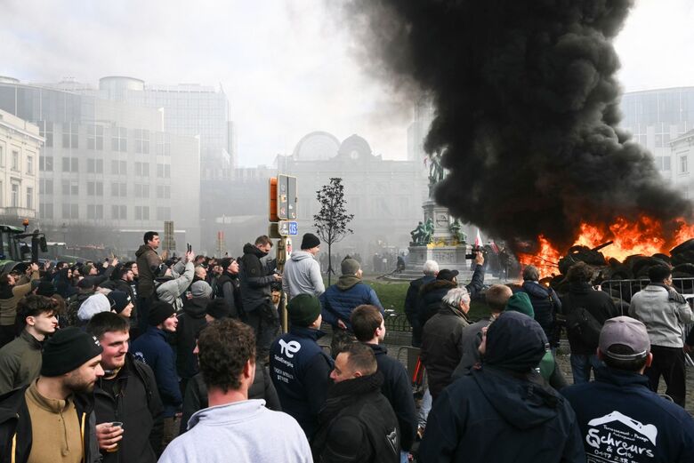 Agricultores protestam ao lado de tratores e de uma fogueira perto do Parlamento Europeu, na Praça de Luxemburgo. | Foto: AFP