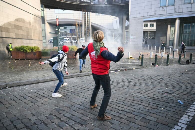 Um manifestante vestindo um colete da Jeunes Agriculteurs (JA, Jovens Agricultores) atira uma batata em direção ao Parlamento Europeu. | Foto: AFP