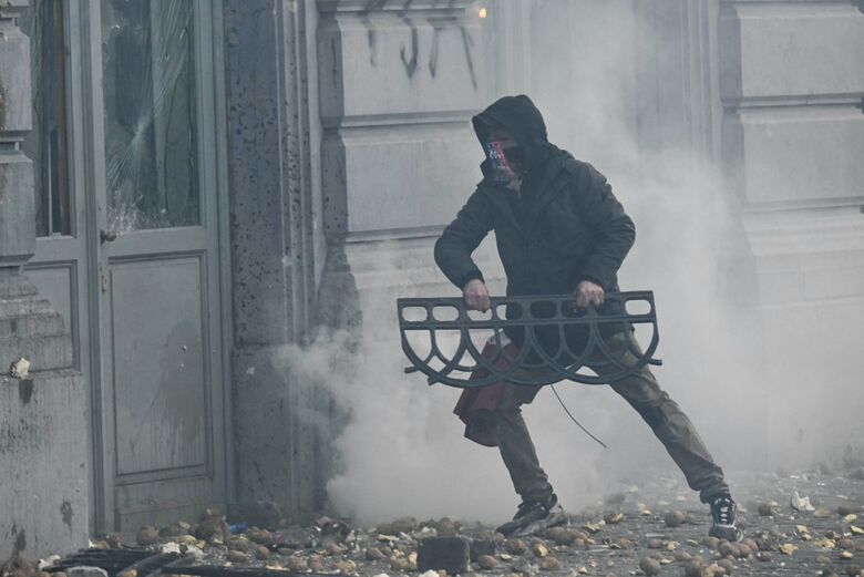 Um manifestante segura uma barricada ao lado da fachada do Parlamento Europeu. | Foto: AFP 