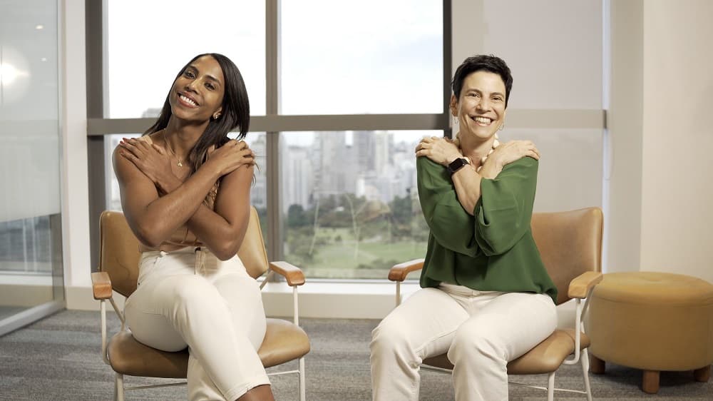 Josy Santos e Juliana Clemente, funcionárias da Amazon engajadas em projetos de incentivo a mulheres na liderança, posando para foto da campanha #EmbraceEquity - #AbraceAEquidade para o Dia Internacional da Mulher