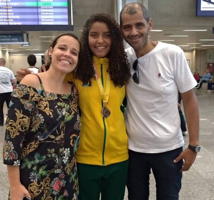 Giovanna traz o ouro. À esquerda, sua mãe Fabíola, à direita, seu pai Cézar