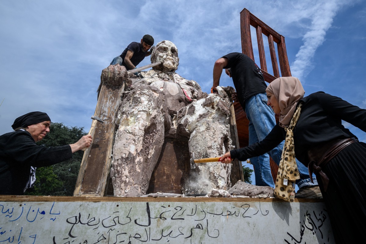 O escultor sírio exilado Khaled Dawwa (acima), com a ajuda de parentes de pessoas desaparecidas na Síria, destrói sua gigantesca obra de arte 