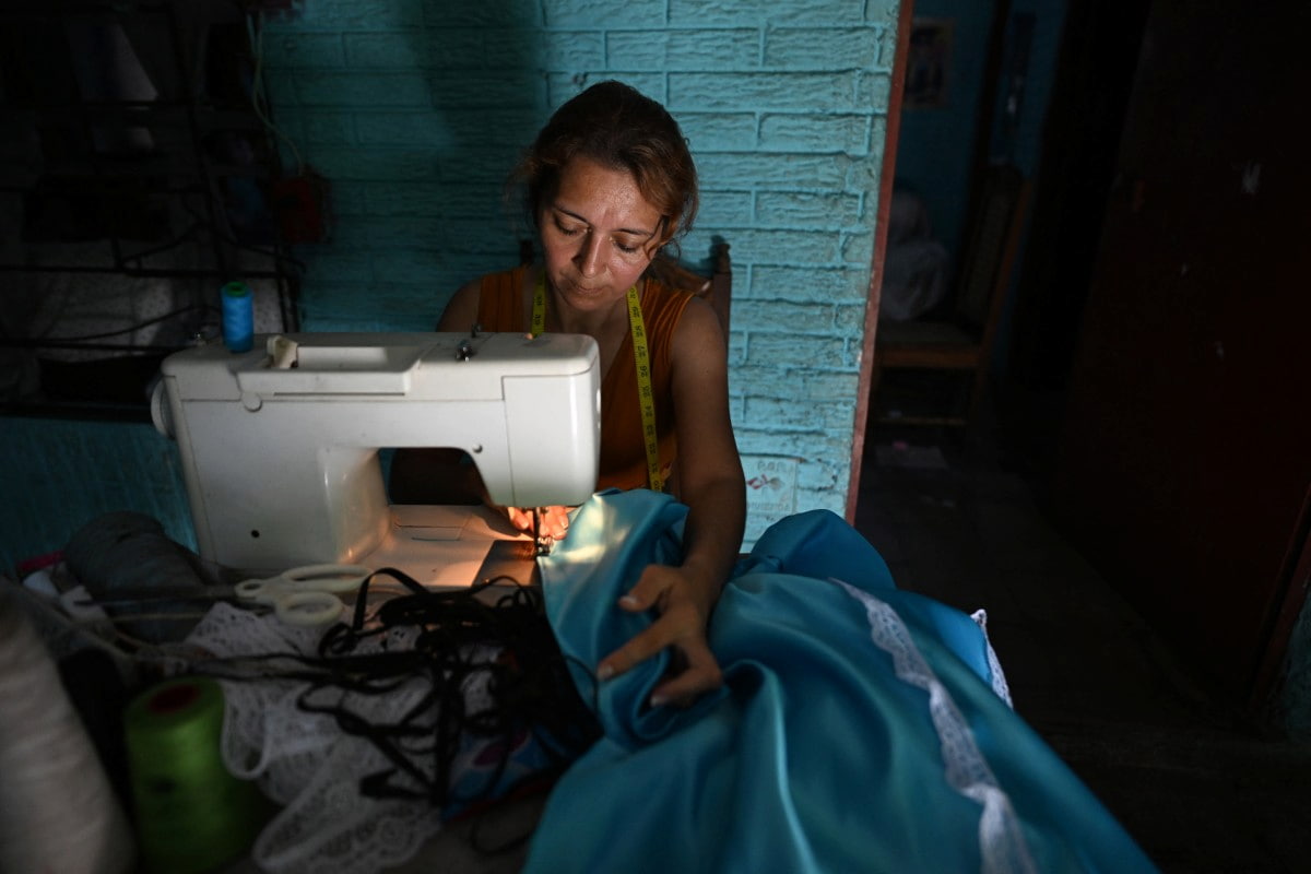 Yessica Mercedes costura um vestido em sua máquina de costura em sua casa em Tonacatepeque, El Salvador