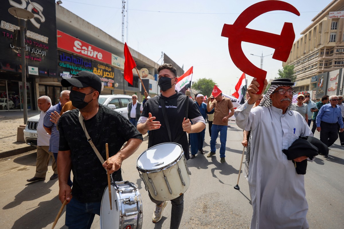 Manifestantes iraquianos seguram bandeiras e gritam slogans enquanto marcham durante um comício do Dia do Trabalho em Bagdá, em 1º de maio de 2025 - Foto de AHMAD AL-RUBAYE / AFP