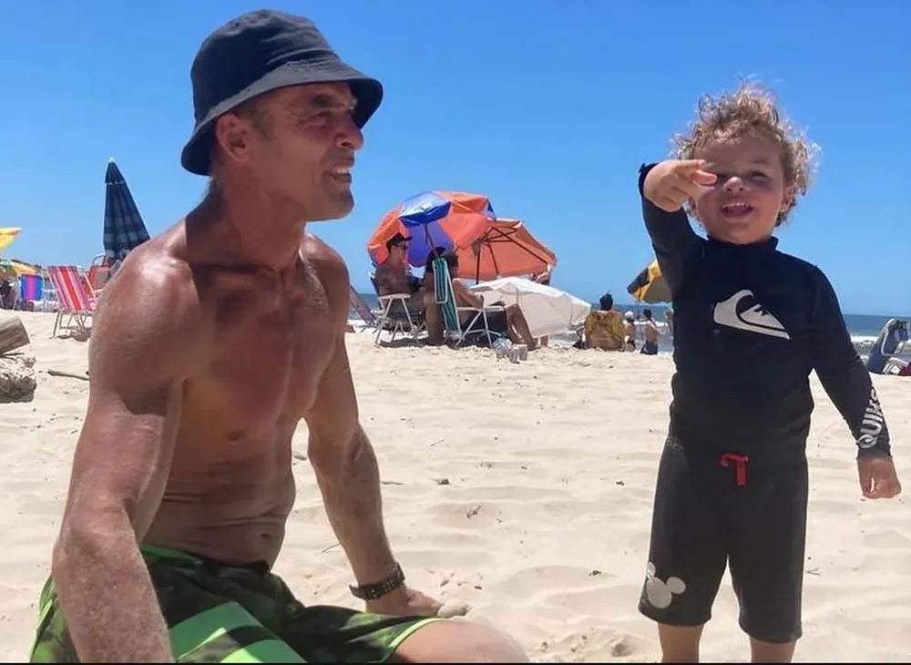 Paulo Zulu com o filho Kiron, de 1 ano, em praia na Guarda do Embaú, em Santa Catarina