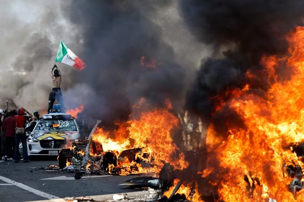 Manifestante segura bandeira mexicana durante protesto contra a polícia migratória dos EUA em Los Angeles