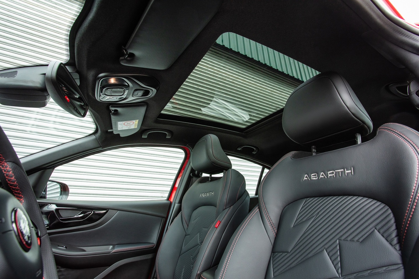 Fastback Abarth 2026 vem com bancos concha em couro com costuras vermelhas. Teto solar panorâmico dá o toque de sofisticação à esportividade. 