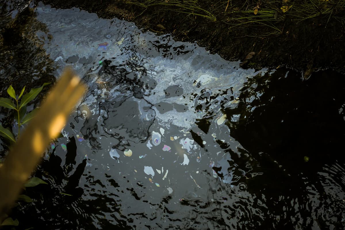 Óleo na água do canal é visível, e o cheiro no local é forte
