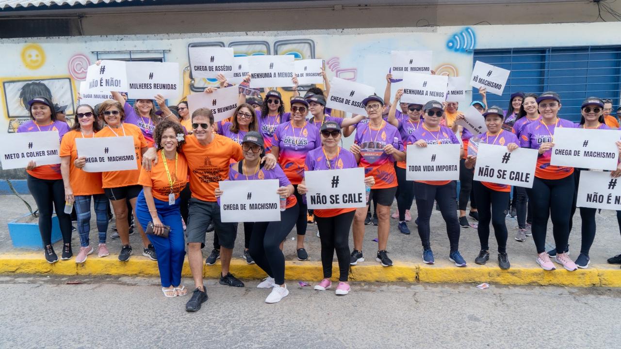 Participantes de 7ª edição erguendo cartazes com mensagens contra o machismo, a misoginia e a qualquer tipo de violência contra mulheres e meninas.